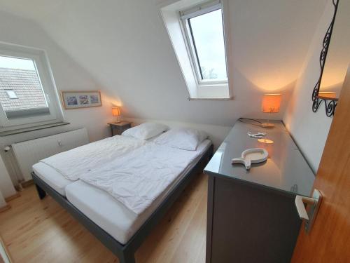 a small bedroom with a bed with a desk and two windows at Am Kampland 25b in Dahme