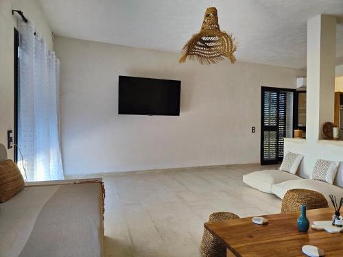 Villa Nour Kélibia في قليبية: غرفة معيشة مع أريكة وتلفزيون على الحائط