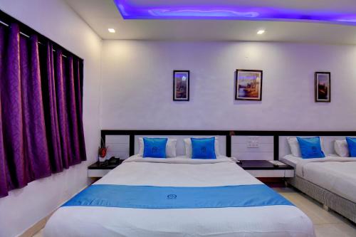 a bedroom with a large bed with blue pillows at Hotel Silver Inn in Mahabaleshwar