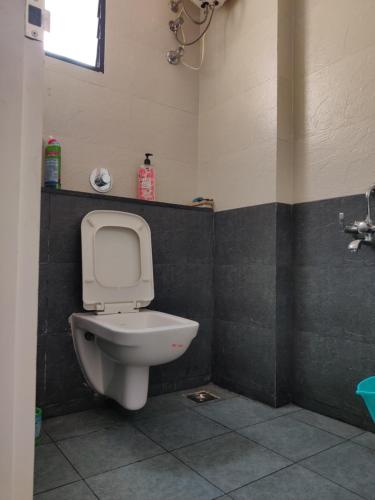 La salle de bains est pourvue de toilettes blanches et d'un mur noir. dans l'établissement Laasya Comforts, à Mangalore