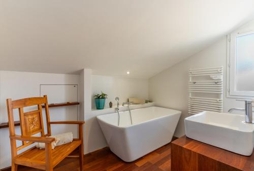 een badkamer met een groot wit bad en een stoel bij Maison Bleue in Capbreton