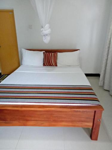 uma cama num quarto com uma moldura de madeira em Binara Holiday Resort em Anuradhapura