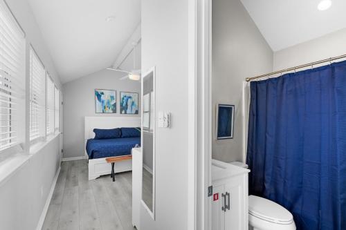 a bathroom with a toilet and a blue shower curtain at Steps to Sand l Ocean views l Smart TVs l Pool in Gulf Shores