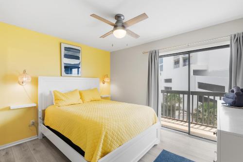 a bedroom with a bed with yellow walls and a window at Steps to Sand l Ocean views l Smart TVs l Pool in Gulf Shores