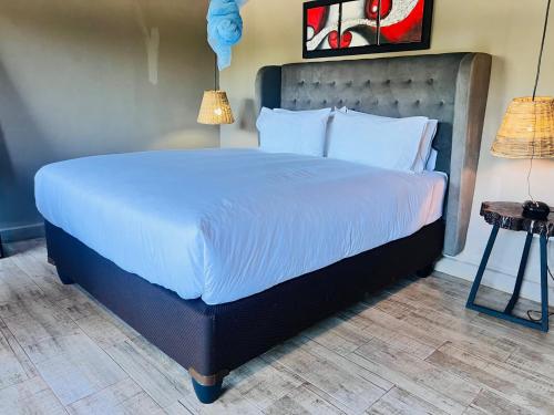 Un dormitorio con una cama grande con sábanas blancas. en The Shed Venue & Boutique Hotel, en Lilongwe