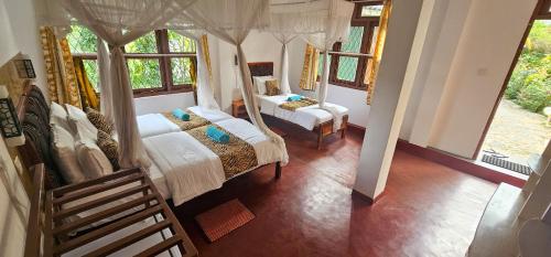 a bedroom with two beds and two windows at Hilltop Guest House in Ella