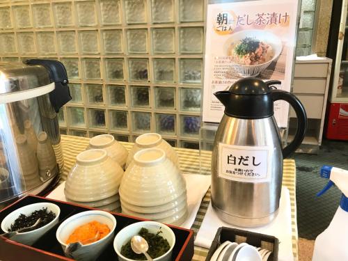 a tea kettle and cups on a counter with bowls at Yokote Central Hotel in Yokote