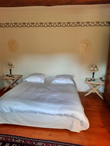 a bedroom with a white bed with two tables at Chambres d'hôtes Le Moulin Juste Ambierle - Loire in Ambierle