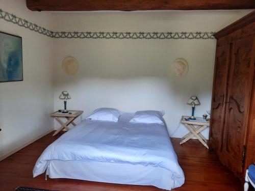 1 Schlafzimmer mit einem weißen Bett und 2 Tischen in der Unterkunft Chambres d'hôtes Le Moulin Juste Ambierle - Loire in Ambierle