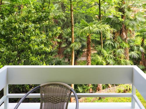 einen Stuhl auf einer Veranda mit Palmen in der Unterkunft Stupendo monolocale in Minusio