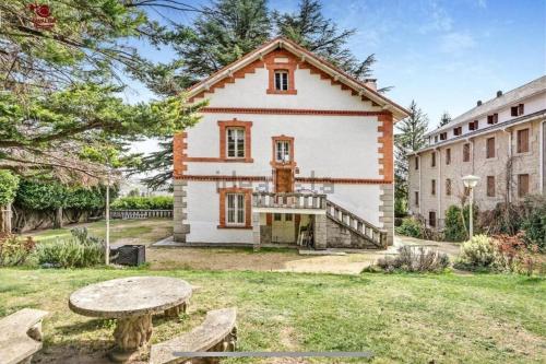 a large white house with a table and benches at Acogedor chalet en la Sierra in Cercedilla