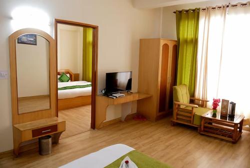 ein Schlafzimmer mit einem Spiegel, einem Bett und einem TV in der Unterkunft Goroomgo New Ambika Mall Road Manali - Prime-location-and-Spacious-Room with Luxury Room And parking Facilities in Manali