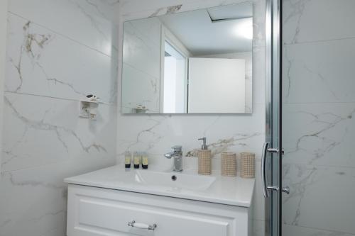 een witte badkamer met een wastafel en een spiegel bij Sea Side Dream-Amazing sea view best location in town in Eilat