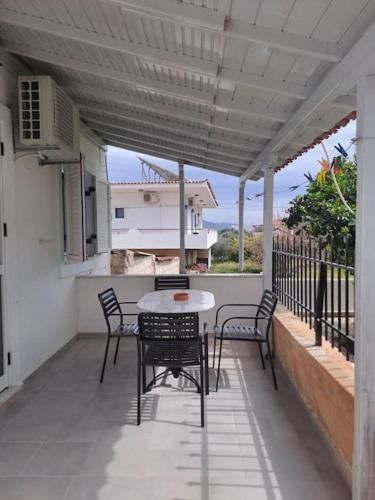 patio con mesa y sillas en el balcón en Flisvos Home Studio, en Megalochori