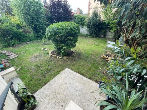 un petit jardin avec une pelouse et un banc dedans dans l'établissement Joli studio indépendant et jardin, à Saint-Prix