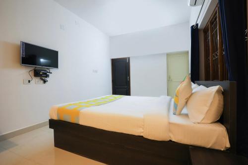 Schlafzimmer mit einem Bett und einem TV an der Wand in der Unterkunft Super OYO JANAPATH INN in Khandagiri