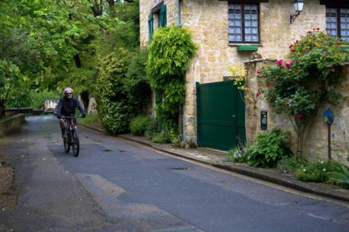 a person riding a bike down a street at L'ESTAMPE in Auvers-sur-Oise