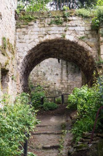 an old brick wall with an archway in a garden at L'ESTAMPE in Auvers-sur-Oise
