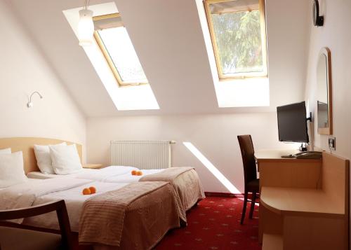 a hotel room with two beds and a desk and two windows at Hotel Nad Mrogą in Koluszki