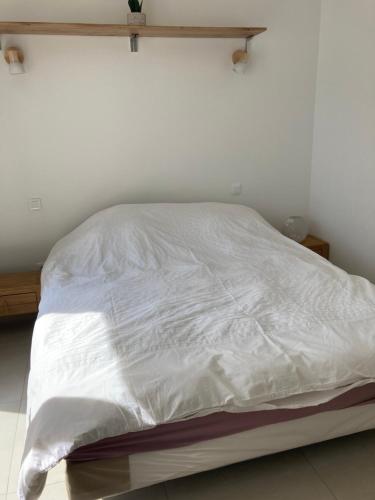 Cette chambre comprend un lit avec des draps blancs. dans l'établissement Studio à louer style loft, à Mantes-la-Jolie