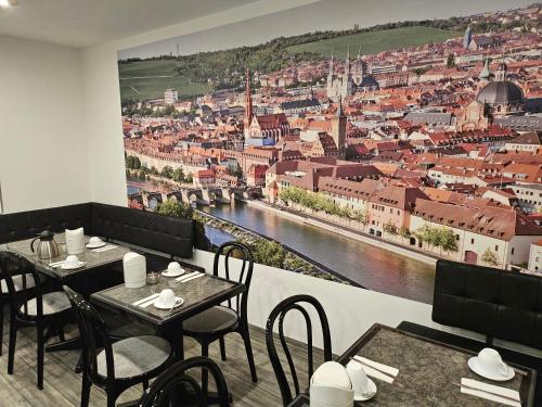 維爾茨堡的住宿－女王酒店，一间设有桌椅的餐厅,并拥有城市壁画