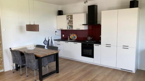 a kitchen with white cabinets and a wooden table at Logement 1860 in Nieuw-Amsterdam