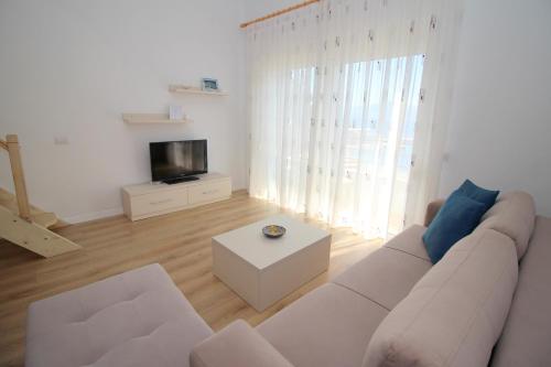 a living room with a white couch and a tv at Blue Residence in Sarandë