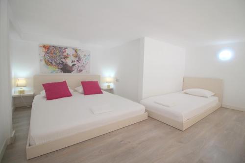 two beds in a white room with red pillows at Blue Residence in Sarandë
