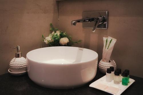 a white sink in a bathroom with flowers on a counter at Bir Valley Retreat in Bīr