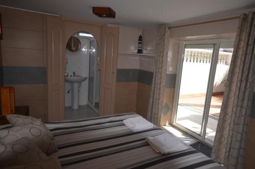 a bedroom with a bed and a bathroom with a sink at Les appartements de la Villa Beida in Oualidia