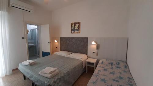 sypialnia z 2 łóżkami i lustrem w obiekcie Hotel Luana w Rimini
