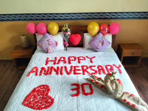 a bed with a happy anniversary sign and balloons on it at Nami House in Ubud