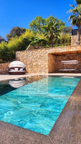 une piscine avec deux chaises et un mur en pierre dans l'établissement Villa Alina, un havre de paix, à Cagnes-sur-Mer