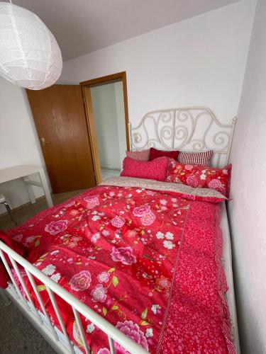 a bedroom with a bed with red blankets and pillows at schöne Ferienwohnung in Meckenbeuren