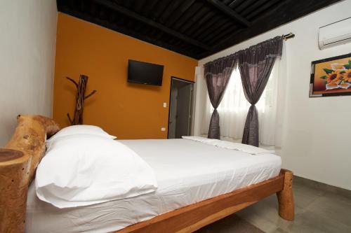 a bedroom with a bed with white sheets and a window at Hotel flamencamarones in Camarones