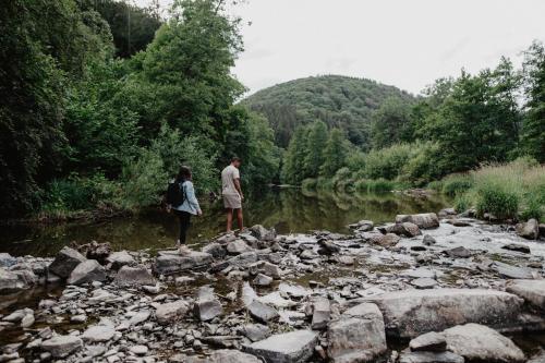 a man and a woman standing on a rocky river at Hotel Cornelyshaff in Heinerscheid