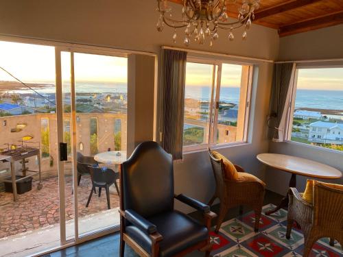 a room with a table and chairs and windows at Agulhasbestview in Agulhas