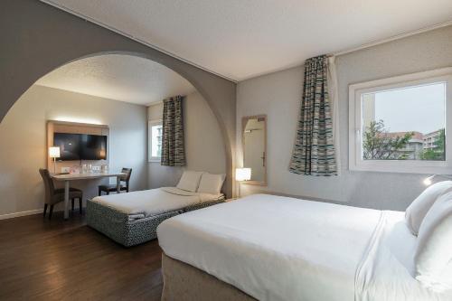 een slaapkamer met een bed en een tafel met een stoel bij Kyriad Marseille Palais Des Congrès – Vélodrome in Marseille
