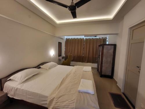 a bedroom with a large white bed with a ceiling at Palm Crest The Colva Diaries in Colva