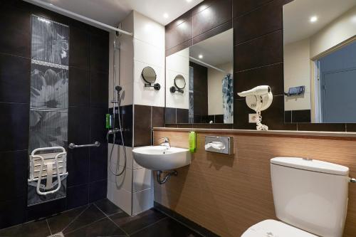een badkamer met een toilet, een wastafel en een spiegel bij Kyriad Marseille Palais Des Congrès – Vélodrome in Marseille