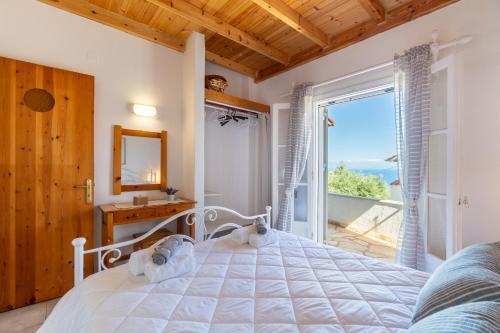 a bedroom with a white bed and a large window at Euterpe's house CORFU in Barbati