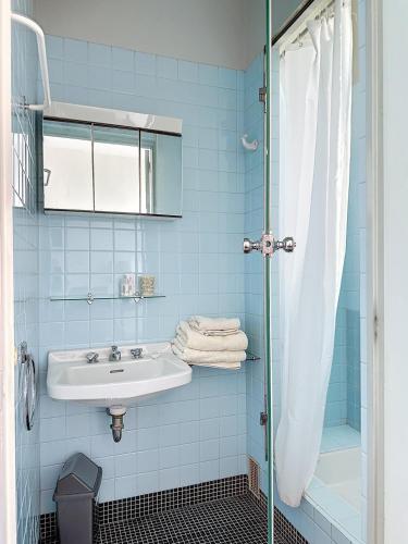 La salle de bains bleue est pourvue d'un lavabo et d'une douche. dans l'établissement AGENCIA dernier étage vue mer panoramique, à Cannes