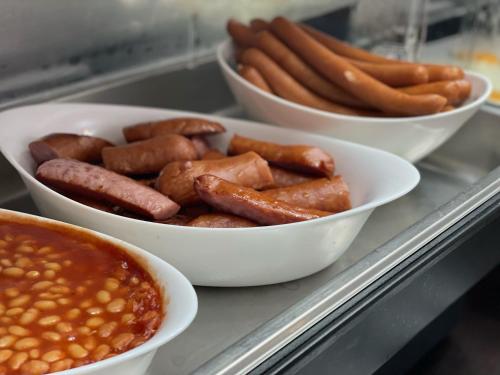 three bowls of hot dogs and beans on a counter at Hotel Willa Adriana in Płock