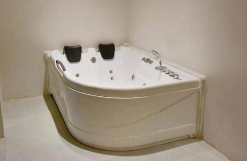 فندق ليان بارك Lian Park Hotel في الخبر: حوض استحمام أبيض في زاوية من الغرفة