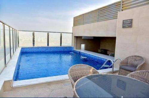 una piscina en un edificio con sillas y mesa en فندق ليان بارك Lian Park Hotel, en Al Khobar