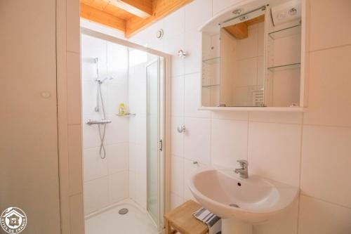a white bathroom with a sink and a shower at Goulapie, Village de gîtes in Saint-Quentin-sur-Sauxillanges