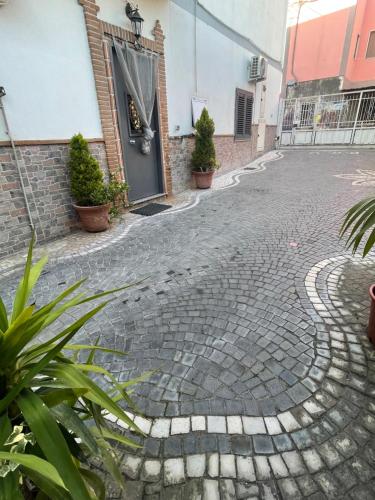 een geplaveide straat met planten voor een deur bij B&b La felicità in Castellammare di Stabia