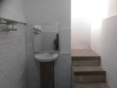 uma casa de banho com lavatório, espelho e escadas em Rain homestay em Selong