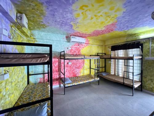 a room with three bunk beds and a colorful ceiling at Santa Maria Hostel Kovalam in Kovalam