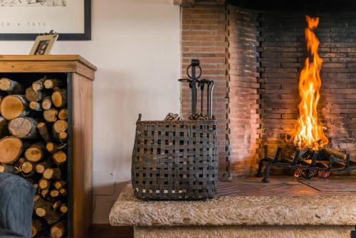 a fireplace with a fire in a room with logs at Villa Renaissance: in Maremma, vicina al mare in Pescia Fiorentina